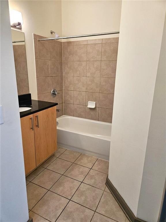 bathroom featuring tile patterned flooring, shower / bathtub combination, and vanity