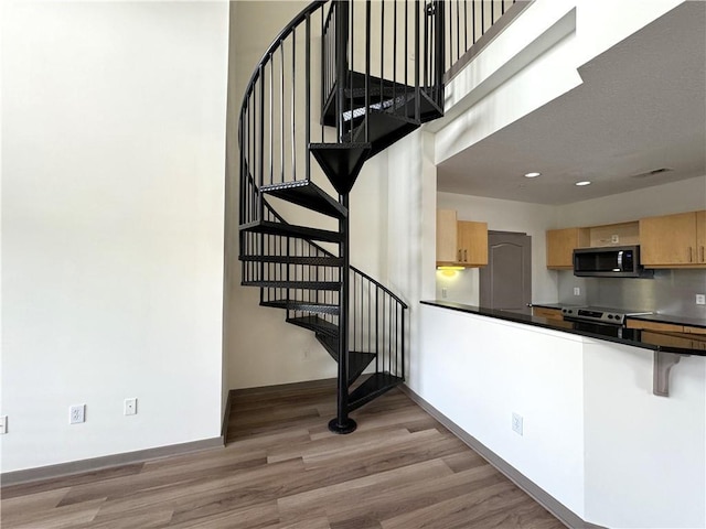 stairs with wood finished floors, baseboards, and recessed lighting