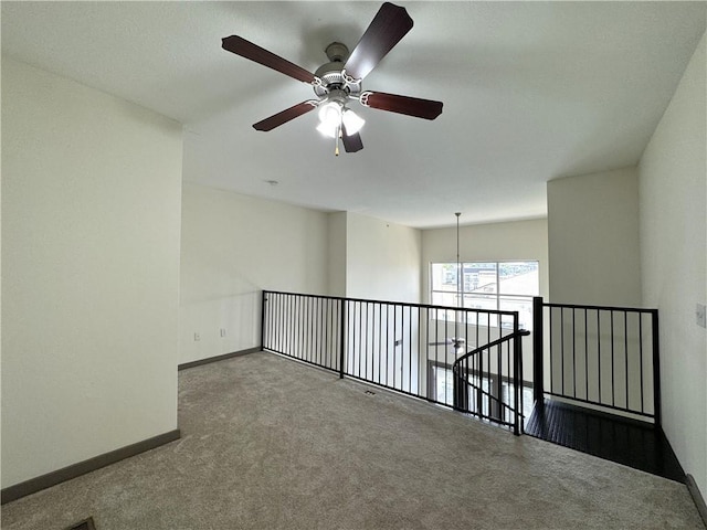 empty room featuring carpet flooring, a ceiling fan, and baseboards