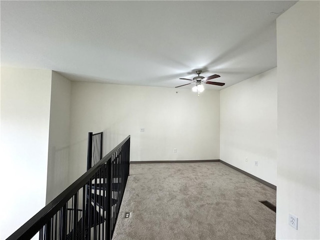 carpeted spare room featuring ceiling fan and baseboards