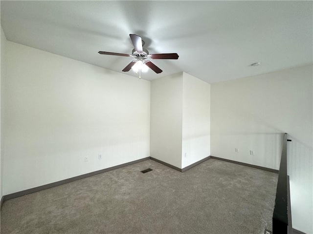 carpeted spare room with a ceiling fan and baseboards