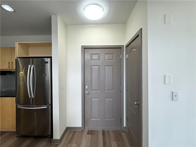 doorway featuring wood finished floors, a textured ceiling, and baseboards