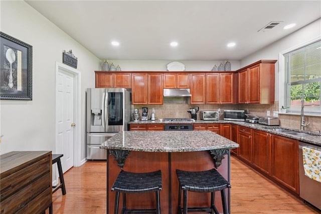 852 Van Briggle Path, Sugar Hill, GA 30518 - kitchen with appliances with stainless steel finishes, under cabinet range hood, backsplash, light stone countertops, and a center island