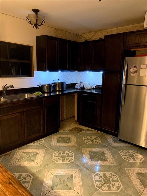 kitchen featuring dark brown cabinetry, stainless steel fridge, and sink