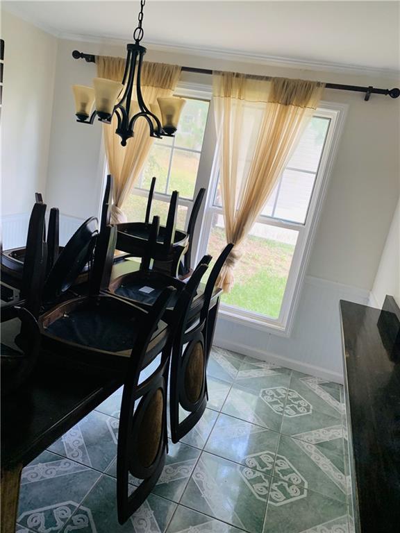 tiled dining room featuring a notable chandelier and a wealth of natural light