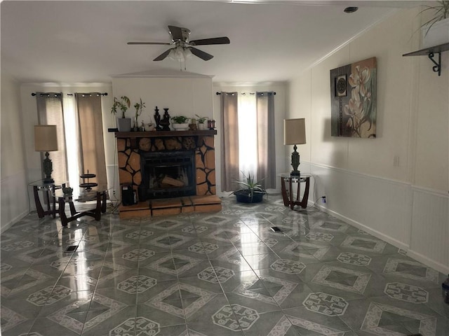 living room featuring a stone fireplace, plenty of natural light, and ceiling fan