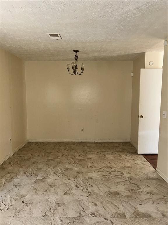 unfurnished room featuring visible vents, a textured ceiling, and an inviting chandelier