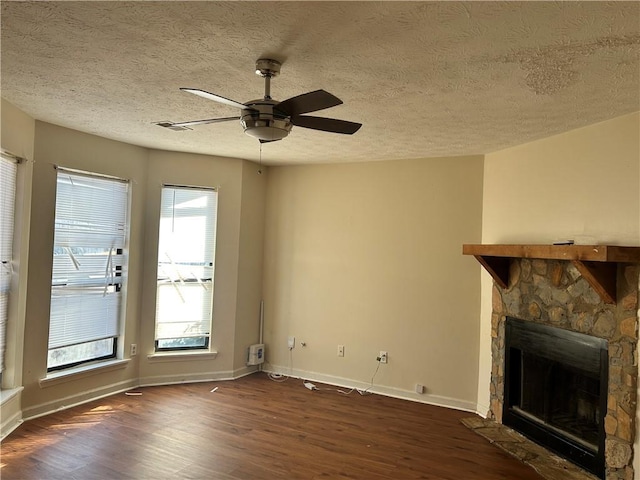 unfurnished living room featuring baseboards, dark wood-style floors, ceiling fan, a textured ceiling, and a fireplace