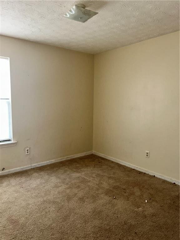 spare room featuring carpet flooring, a textured ceiling, and baseboards