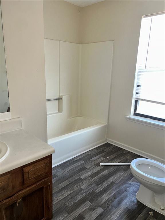 full bathroom featuring baseboards, toilet, wood finished floors, vanity, and shower / washtub combination