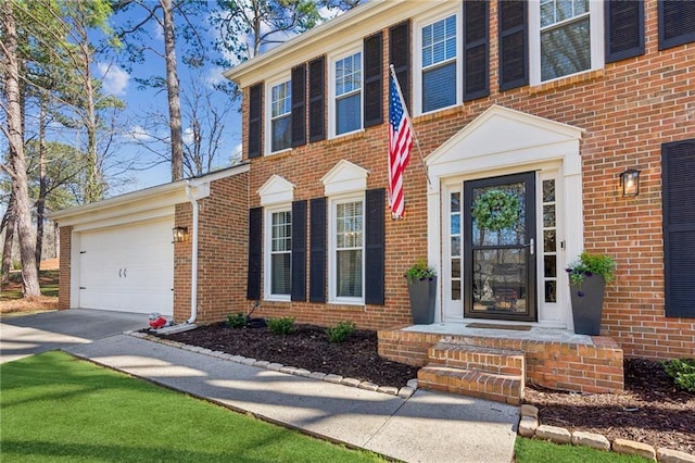 entrance to property with brick siding, driveway, and an attached garage