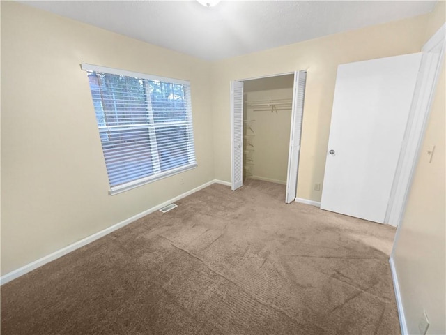 unfurnished bedroom with light colored carpet and a closet