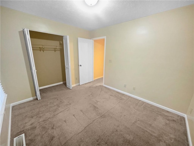 unfurnished bedroom with light carpet, a closet, and a textured ceiling