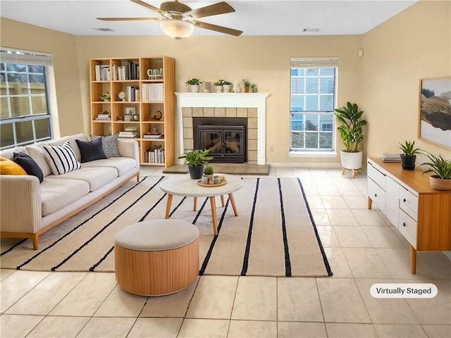 tiled living room with ceiling fan and a fireplace