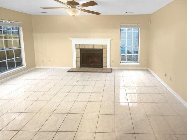 unfurnished living room with a tiled fireplace, ceiling fan, and light tile patterned flooring