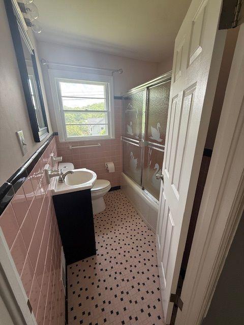 2190 Olive Springs Rd SE, Marietta, GA 30060 - full bath with tile walls, toilet, shower / bath combination with glass door, vanity, and a wainscoted wall