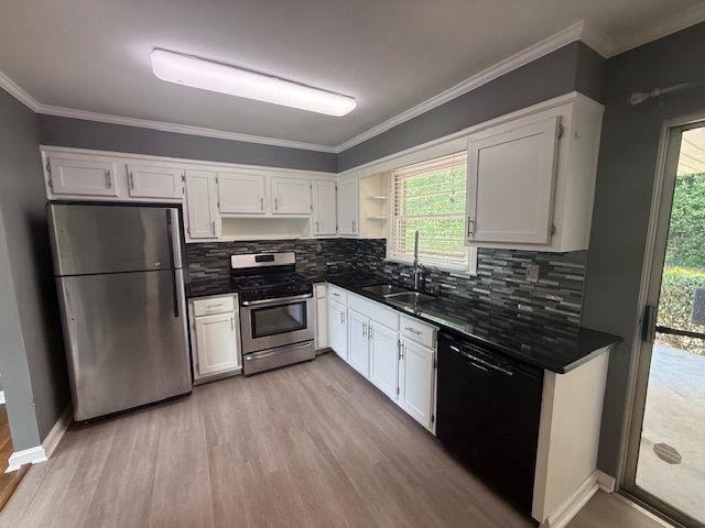 2190 Olive Springs Rd SE, Marietta, GA 30060 - kitchen featuring appliances with stainless steel finishes, a sink, light wood-style flooring, white cabinetry, and crown molding