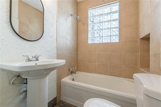 bathroom with toilet and tiled shower / bath