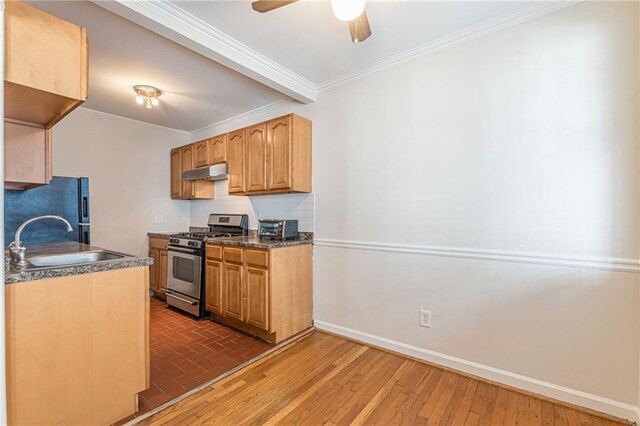 kitchen featuring black refrigerator, ornamental molding, sink, dark hardwood / wood-style floors, and stainless steel range with gas cooktop