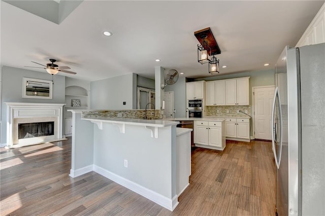 4770 Spring Park Cir, Suwanee, GA 30024 - kitchen with stainless steel appliances, open floor plan, an island with sink, wood finished floors, and light countertops