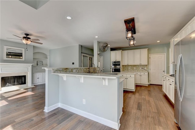 4770 Spring Park Cir, Suwanee, GA 30024 - kitchen with appliances with stainless steel finishes, a breakfast bar area, wood finished floors, open floor plan, and a fireplace