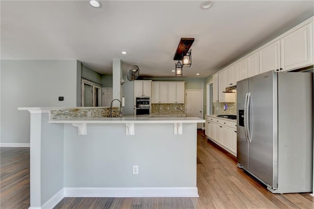 4770 Spring Park Cir, Suwanee, GA 30024 - kitchen with appliances with stainless steel finishes, backsplash, a kitchen breakfast bar, light countertops, and white cabinets