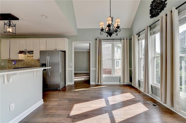 4770 Spring Park Cir, Suwanee, GA 30024 - kitchen with stainless steel fridge with ice dispenser, vaulted ceiling, a kitchen breakfast bar, under cabinet range hood, and light countertops