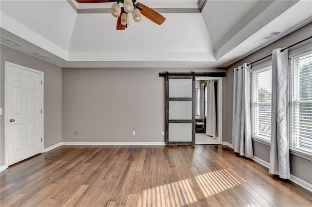 4770 Spring Park Cir, Suwanee, GA 30024 - unfurnished room featuring ceiling fan, wood finished floors, a barn door, vaulted ceiling, and a raised ceiling