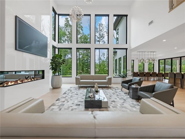 2940 Old Peachtree Rd, Dacula, GA 30019 - living room with a towering ceiling, a chandelier, wood finished floors, a glass covered fireplace, and recessed lighting