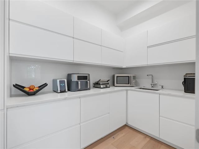 2940 Old Peachtree Rd, Dacula, GA 30019 - kitchen featuring a sink, stainless steel microwave, white cabinetry, light countertops, and light wood finished floors