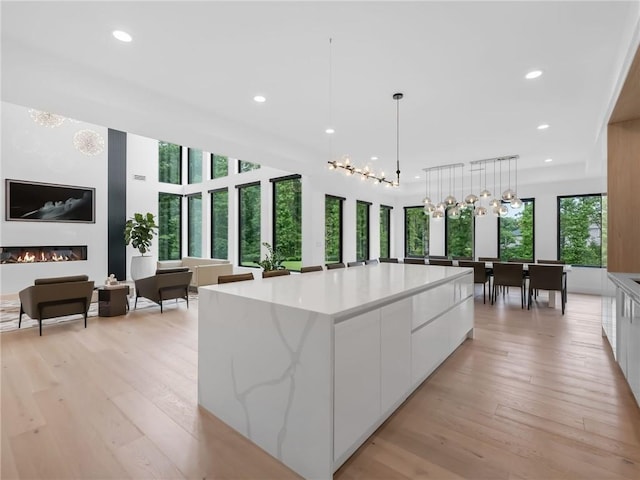 2940 Old Peachtree Rd, Dacula, GA 30019 - kitchen with modern cabinets, white cabinetry, light wood-style floors, a large island, and hanging light fixtures