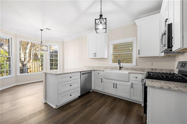 kitchen with a peninsula, appliances with stainless steel finishes, a sink, and white cabinets