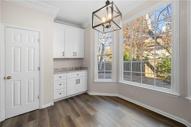 unfurnished dining area featuring a chandelier, dark wood-style floors, baseboards, and crown molding