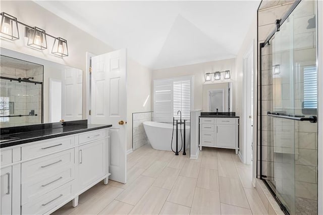 bathroom with a stall shower, a soaking tub, vanity, and vaulted ceiling