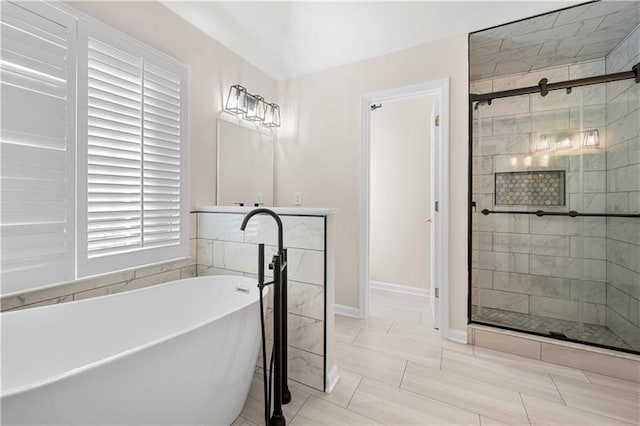 full bath featuring baseboards, a shower stall, and a freestanding tub