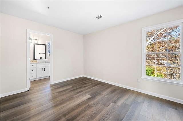 empty room with baseboards, dark wood finished floors, and visible vents