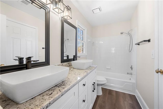 full bathroom featuring a sink, visible vents, wood finished floors, and washtub / shower combination