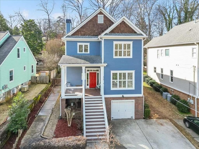 view of front of house with a garage, cooling unit, and a porch