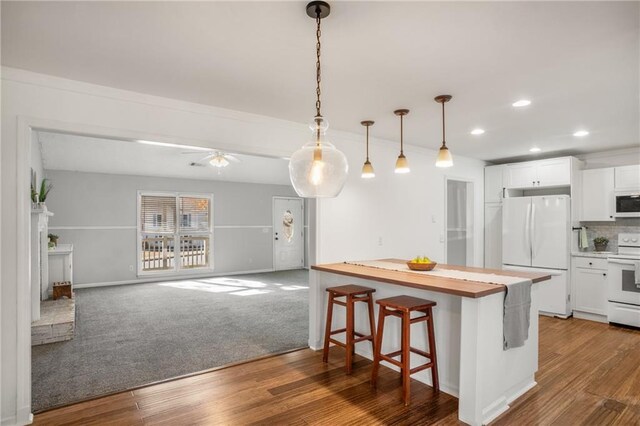 kitchen featuring white appliances, a breakfast bar, decorative backsplash, white cabinets, and decorative light fixtures