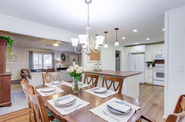 dining room featuring ceiling fan with notable chandelier and light wood-type flooring