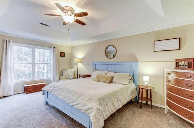 bedroom with crown molding, a tray ceiling, carpet floors, and ceiling fan