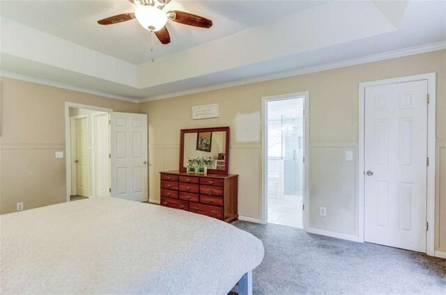 bedroom with ensuite bathroom, carpet flooring, ceiling fan, a tray ceiling, and crown molding