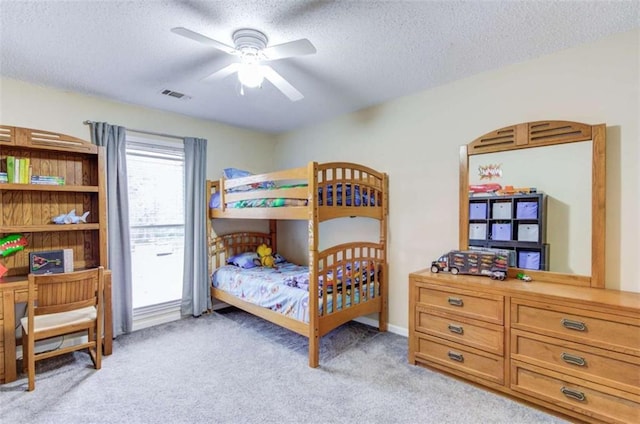 bedroom featuring ceiling fan, light carpet, and a textured ceiling