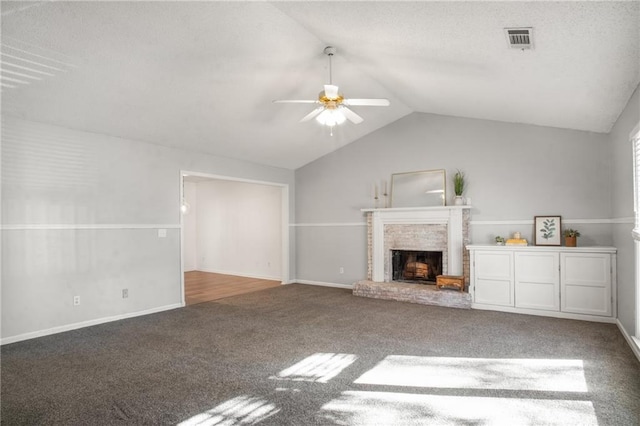 unfurnished living room featuring ceiling fan, a brick fireplace, lofted ceiling, and carpet