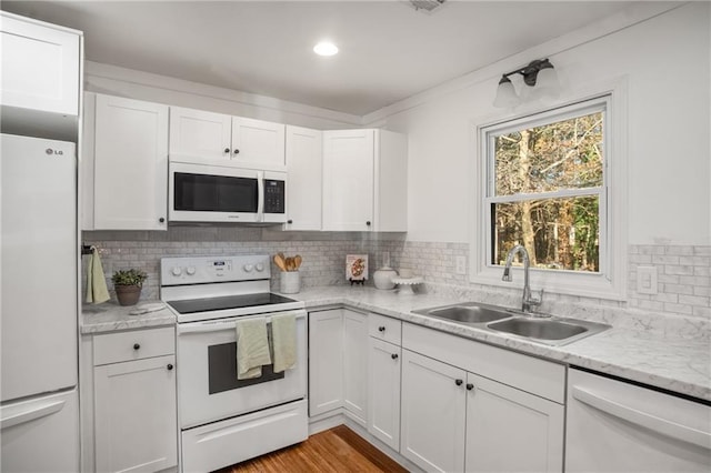 kitchen with white cabinetry, white appliances, sink, and tasteful backsplash