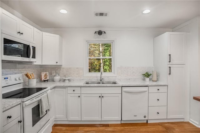 kitchen with sink, light stone counters, white appliances, decorative backsplash, and white cabinets