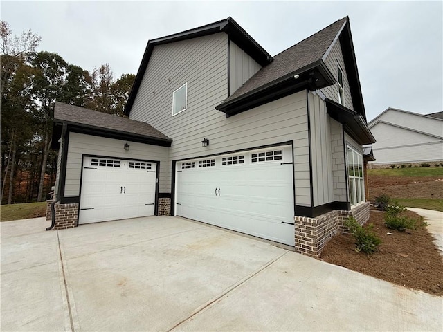 view of side of property featuring an attached garage, brick siding, and driveway