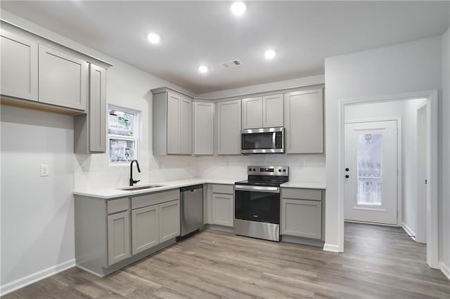 1005 Sims Ave NW, Atlanta, GA 30318 - kitchen with stainless steel appliances, tasteful backsplash, a sink, light wood-style floors, and gray cabinets