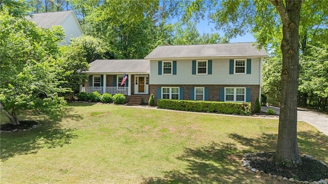 split level home with covered porch, brick siding, and a front lawn