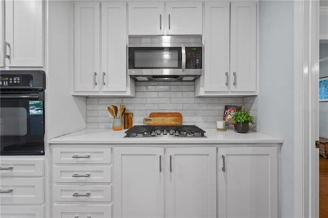kitchen with appliances with stainless steel finishes, white cabinets, light countertops, and backsplash